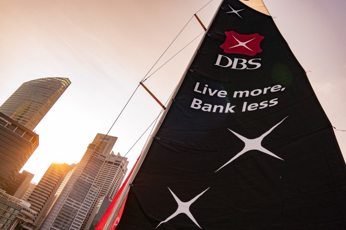 From a tall building hangs a flowing banner with DBS bank logo and their famous tagline, "Live more, Bank less."