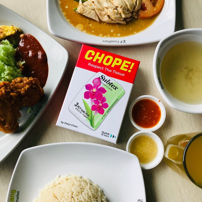 Image of Singaporean board game, Chope!, on a hawker centre table filled with local delights.